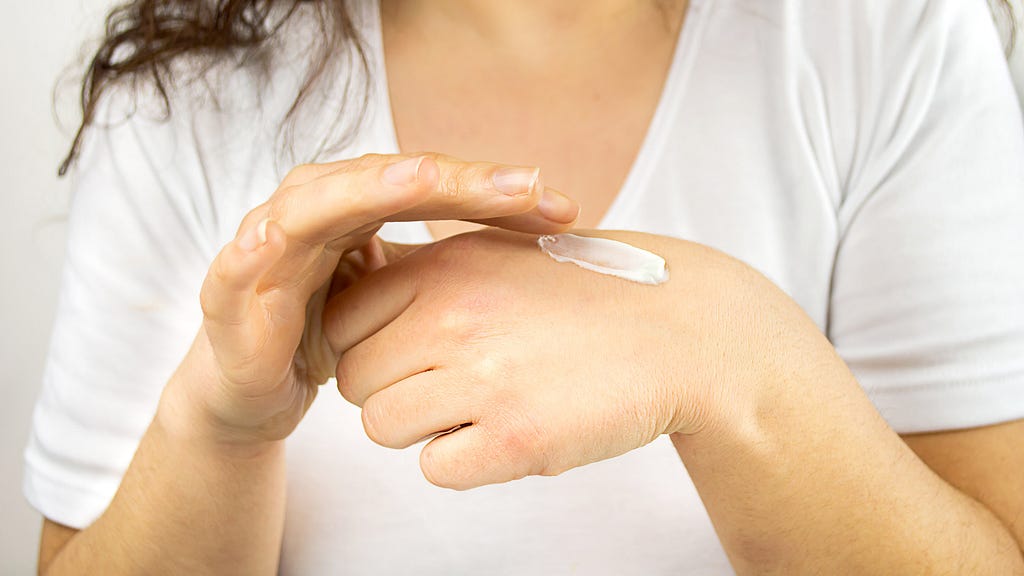 a woman spreads lotion on her hand