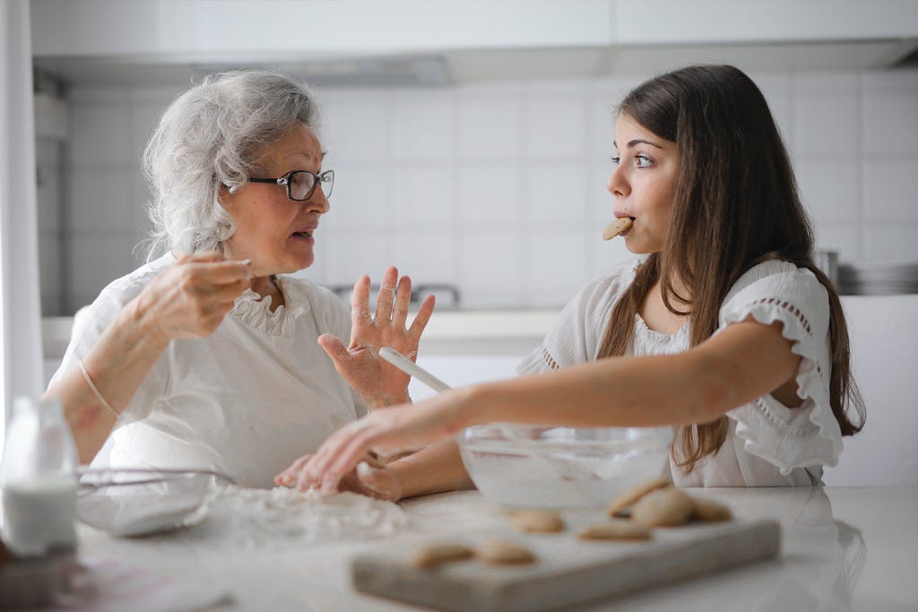 A grandmother with granddaughter having interesting conversation while cooking together in a kitchen