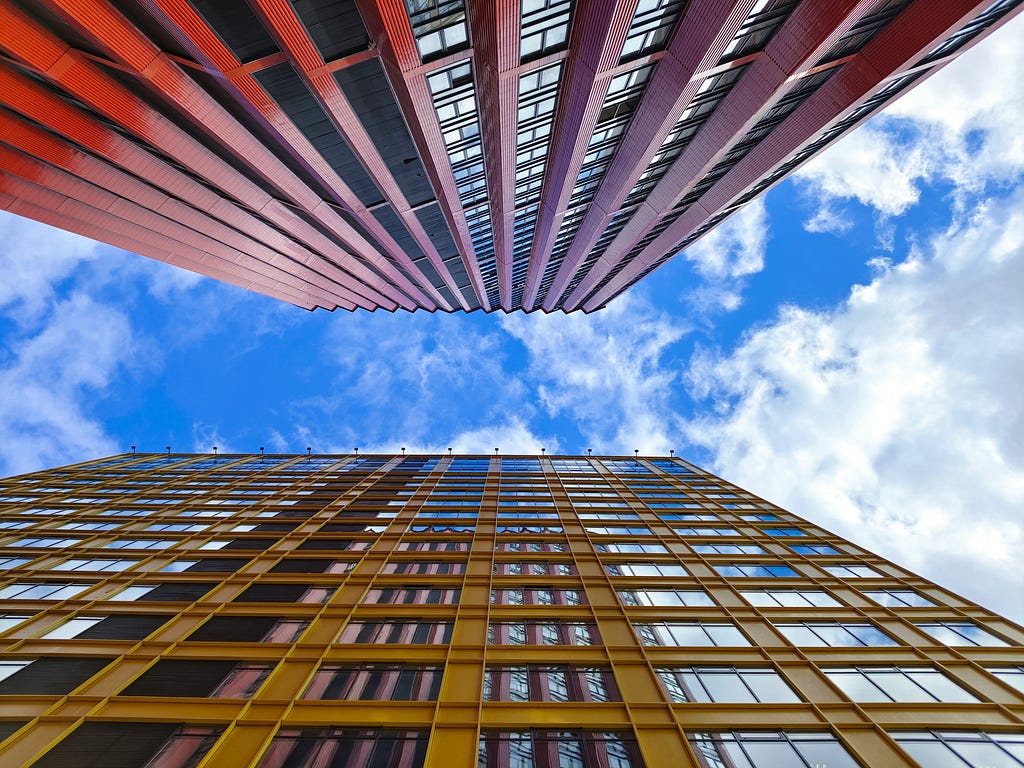 A dramatic view looking up between two tall buildings.