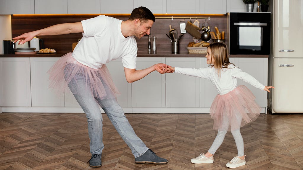 Side view of a girl in a tutu skirt having fun with her dad, both wearing tutu skirts and laughing.