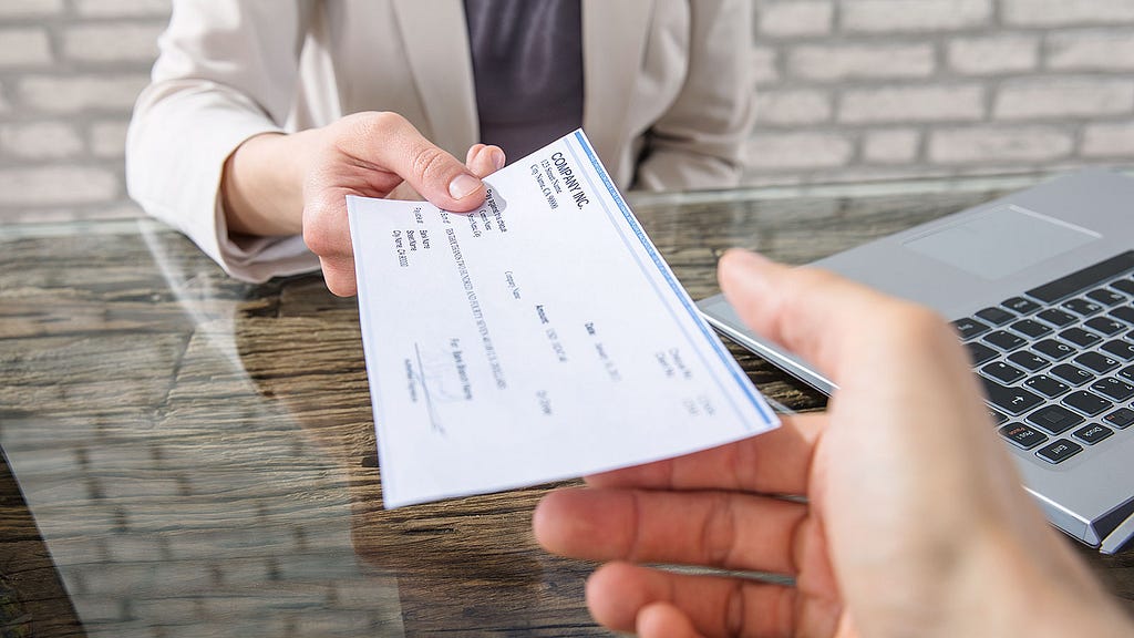 A employer handing an employee a paper check