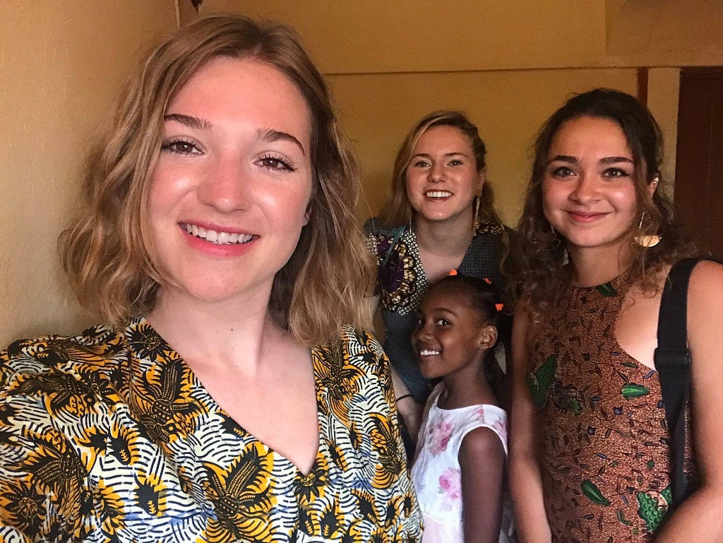 Elizabeth Rhoads takes a selfie with three other people behind her, including two students from GlobeMed at the George Washington University and a young Ugandan girl.