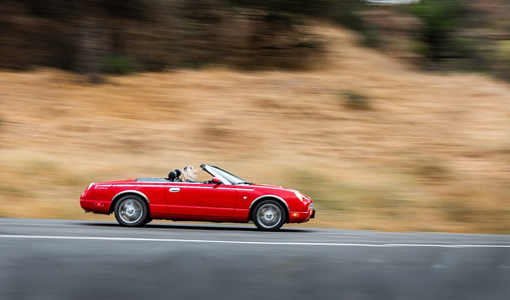 Red sexy car zooming on the road.