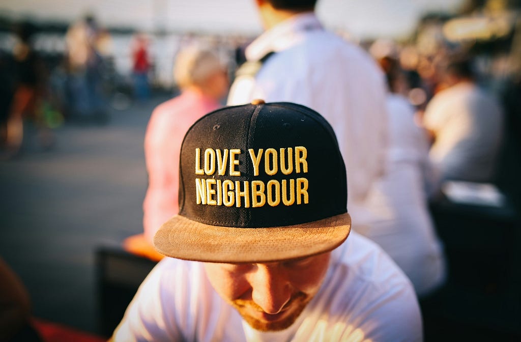 Man wearing ballcap that says “Love your neighbor”