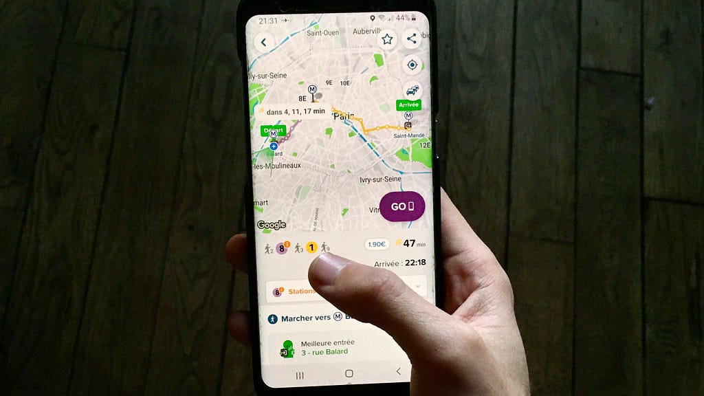 A hand holding a smartphone displaying the app Citymapper.