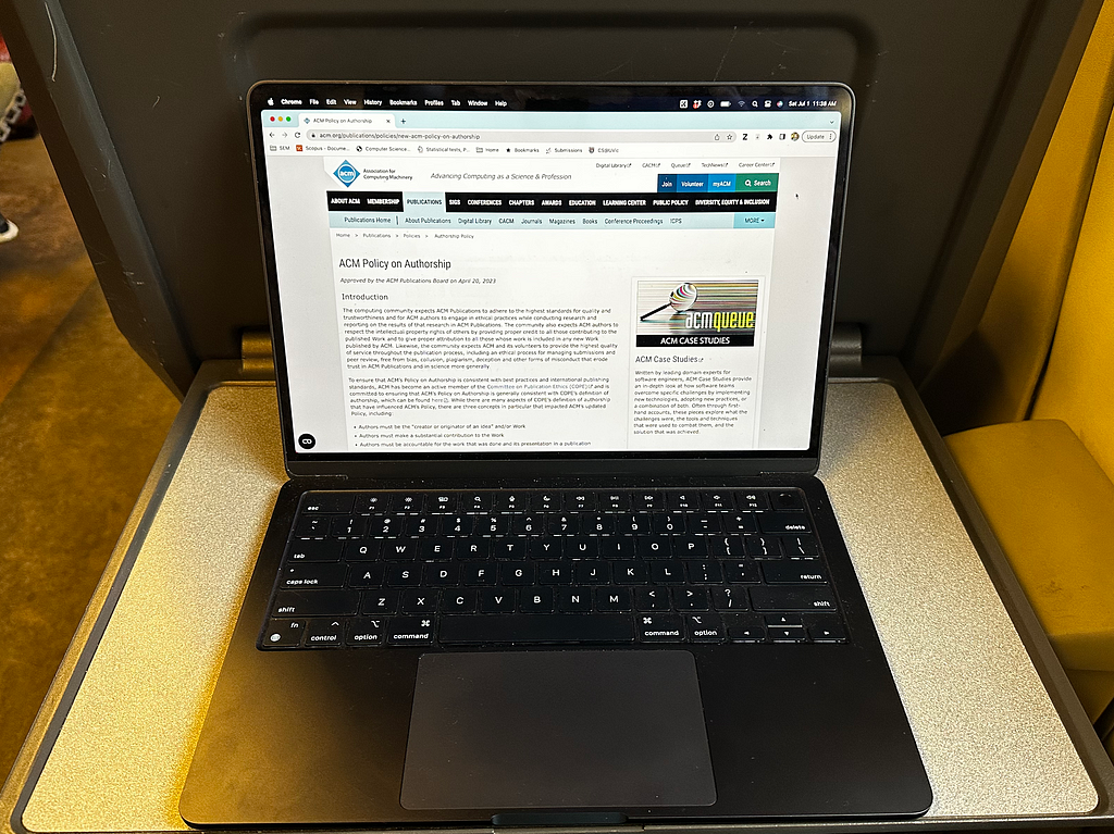 A laptop being used by a commuter working while traveling sustainably on a train; the screen is showing the website with the ACM Authorship Policy. The reader was so engaged by the policy that she missed her train connection in Rotterdam and just barely made her flight from Amsterdam.