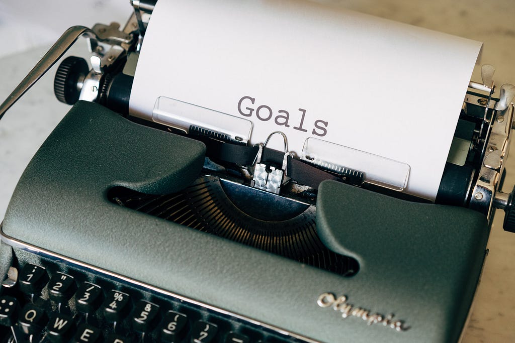 A typewriter with a sheet on which “goal” is written