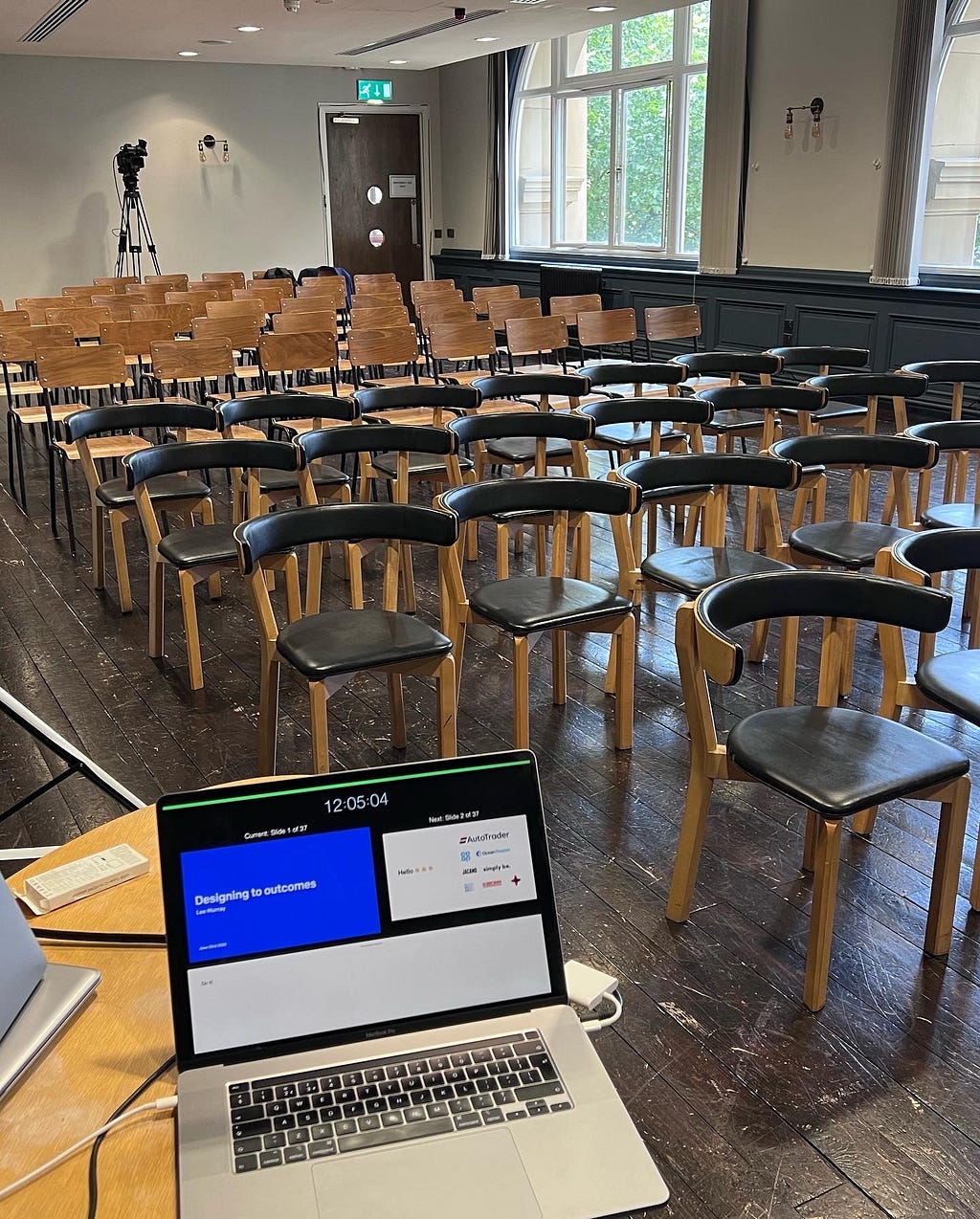 An empty room with chairs and a laptop before the designing to outcomes talk at Camp Digital 2022 by Lee Murray.