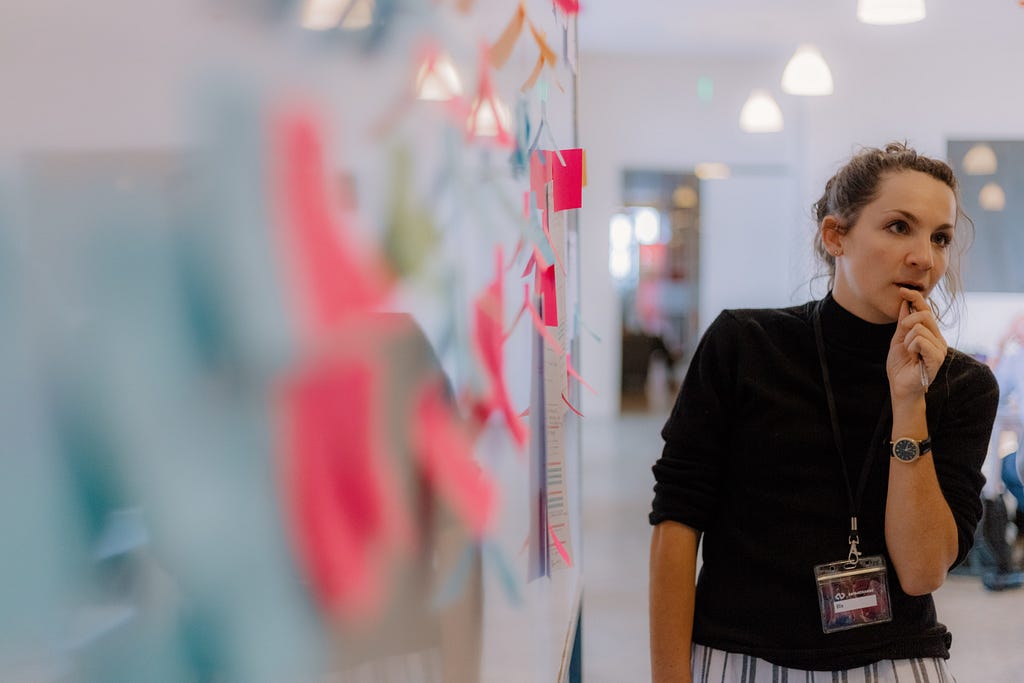 Ella Hollowood standing in front of a whiteboard filled with post-it notes at the Data4Change 2019 sprint in Nairobi.