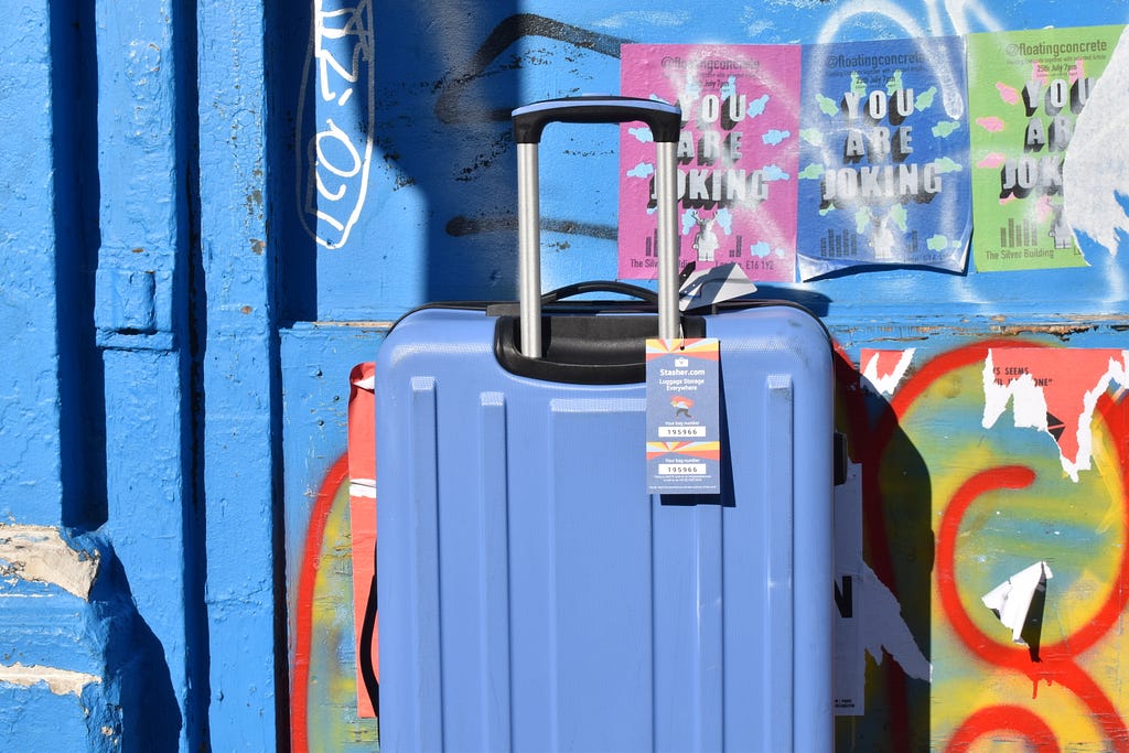 Blue Stasher suitcase set against a graffiti covered wall