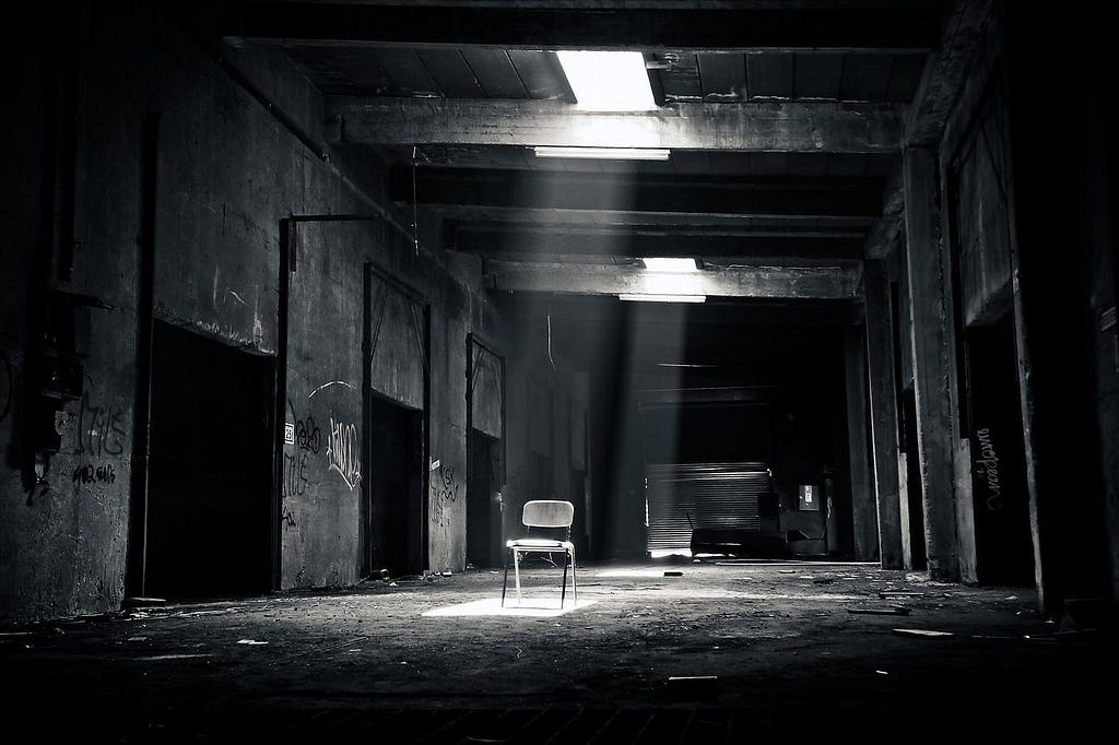 an abandoned building with light falling onto a chair