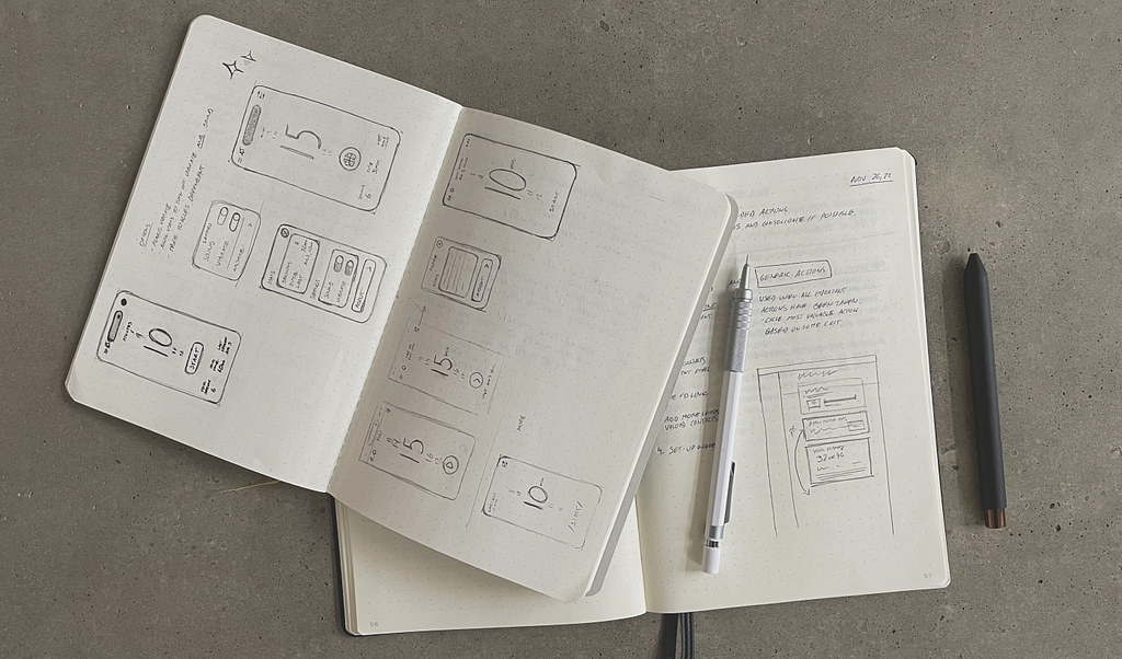 A photo of two sketchbooks pictured from above. A pen is on top of one of them. On their pages, there are sketches of various wireframe ideas.