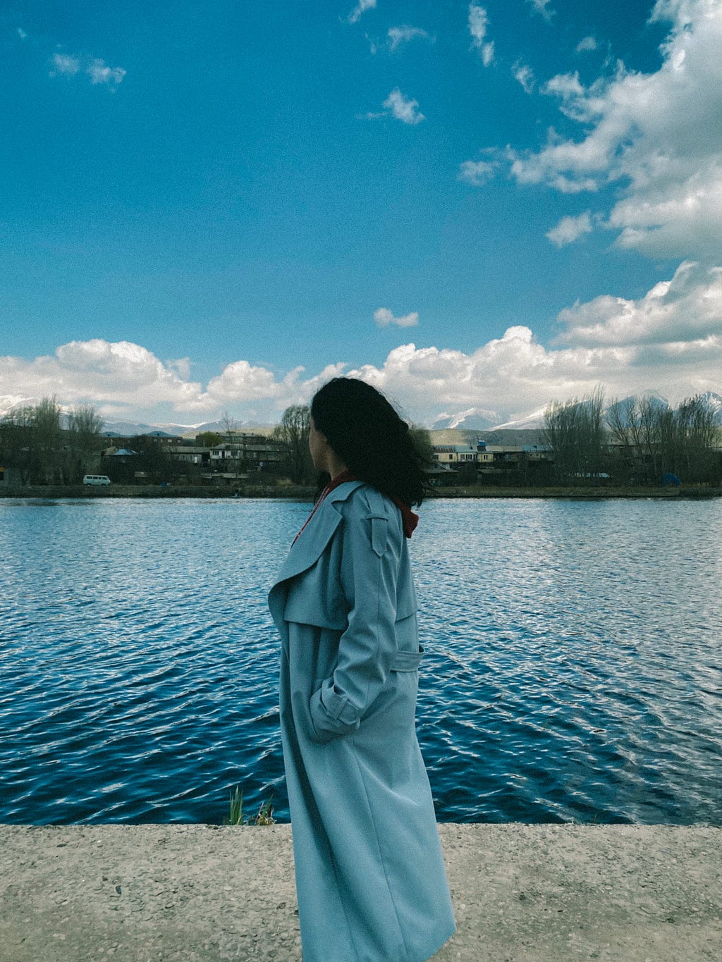 A girl staring at the river behind her.