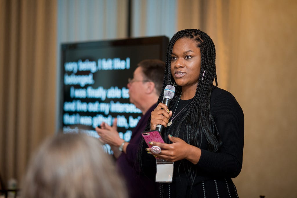 Nakia addresses the 2019 Leadership Institute. Behind her, captioning and an ASL interpreter ensure access to communication.