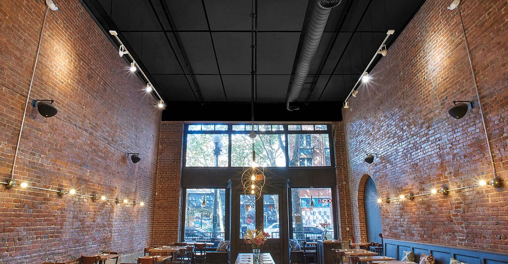 A generic brick-walled, glass-fronted restaurant with a tall loft ceiling.