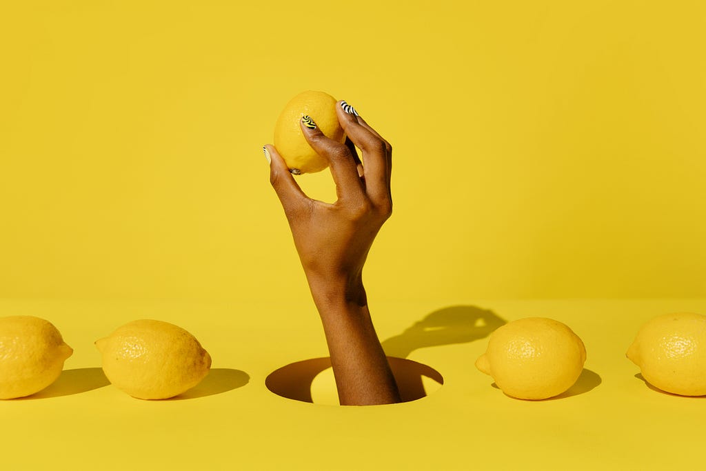 Yellow background with a hand holding a lemon