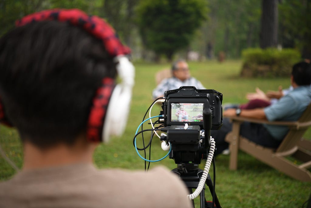 A camera operator films a conversation between three men.