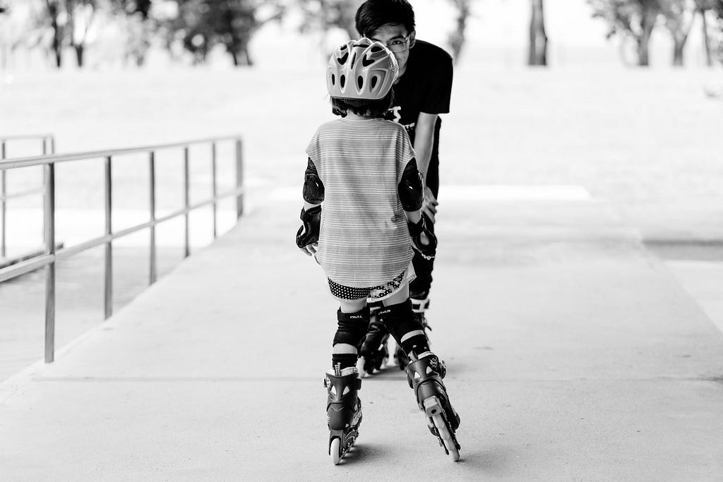 A father teaching his kid to skate.