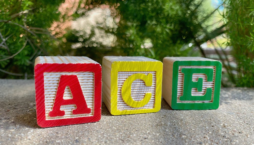 Three colorful wood blocks spelling out “ace.”