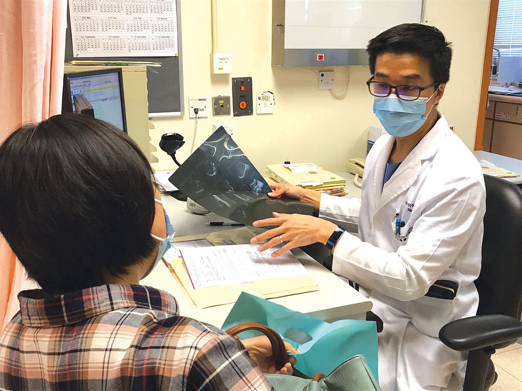 Dr. Walter Seto discuss findings to his patient about an X-ray scan in his clinic