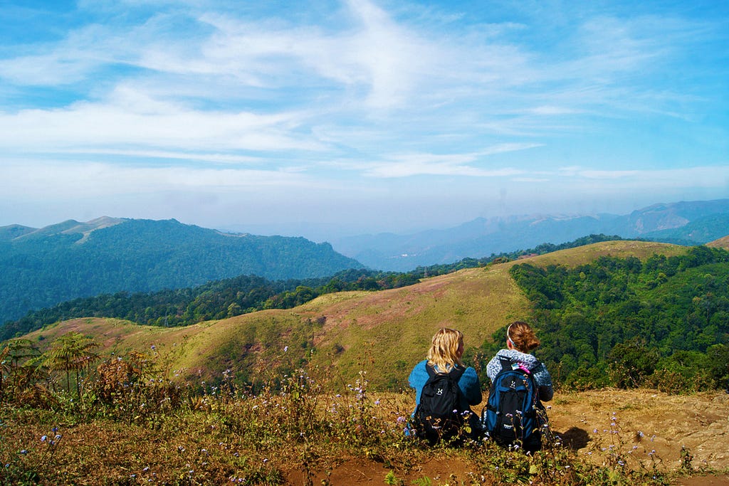 A scenic view of two young travel enthusiasts admiring the beauty of nature from the hills of Gavi in the Pathanamthitta district of Kerala.