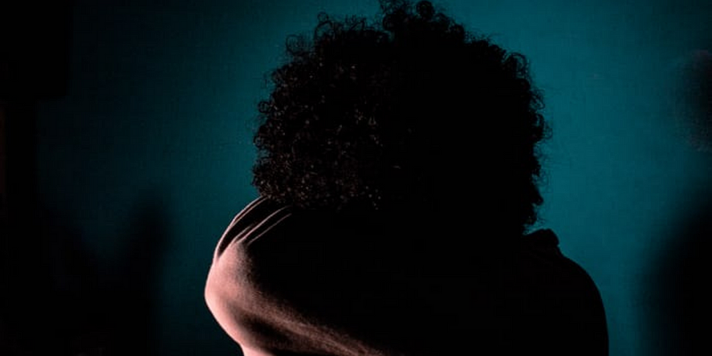 Photo by Carlos Arthur M.R on Unsplash | girl with afro textured hair with back to camera, in the shadows