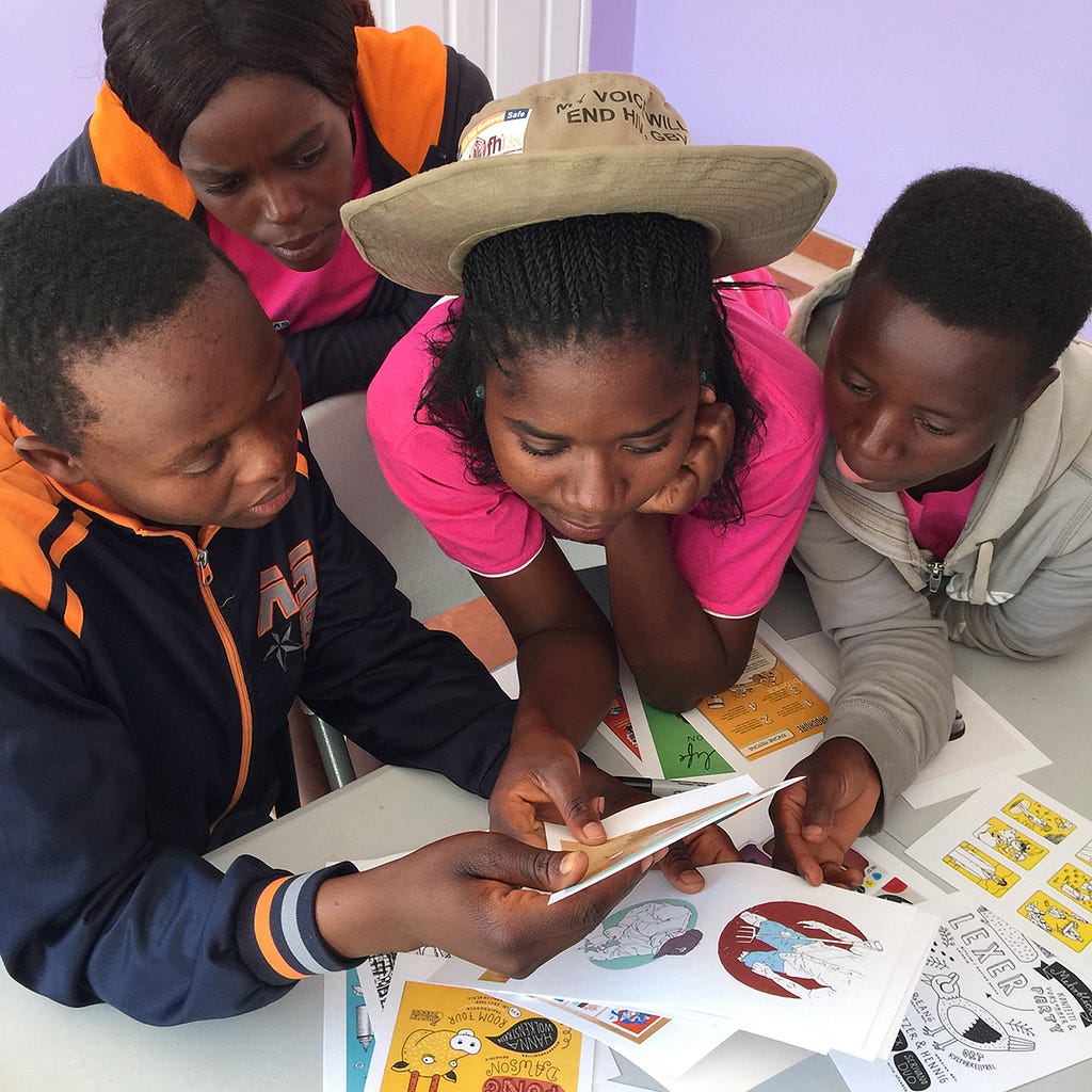 A group 4 children of African descent looking at some colourful cards