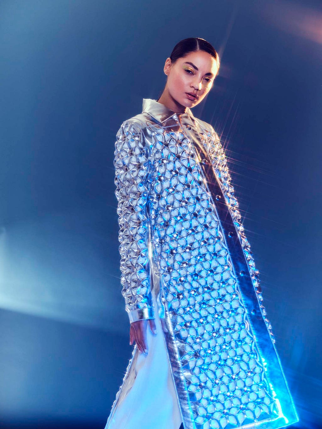 Model in shimmering coat, against blue backdrop