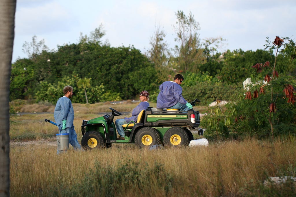 Three volunteers are getting back to ATV with spray guns and buckets where the baited hydrogel is stored.