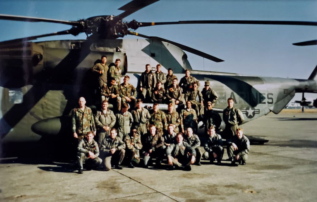 Matthew Brackmann (far right) with his squadron mates in uniform in front of a military helicopter.