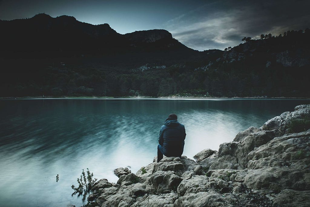 A man in a hoodie facing the lake