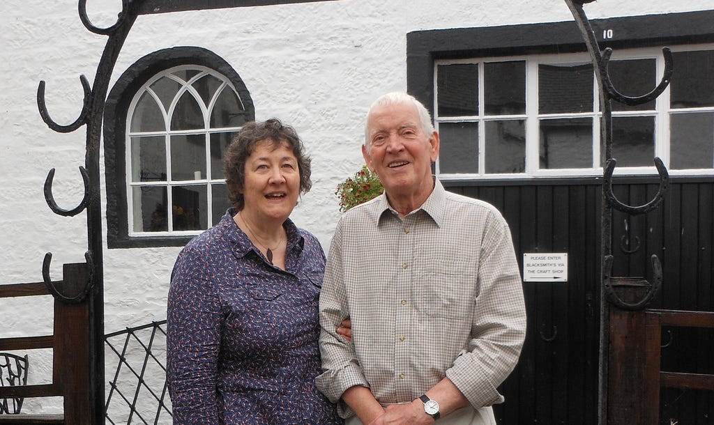 The photo shows Elizabeth Pepper and her late husband Alan standing together in front of a building.