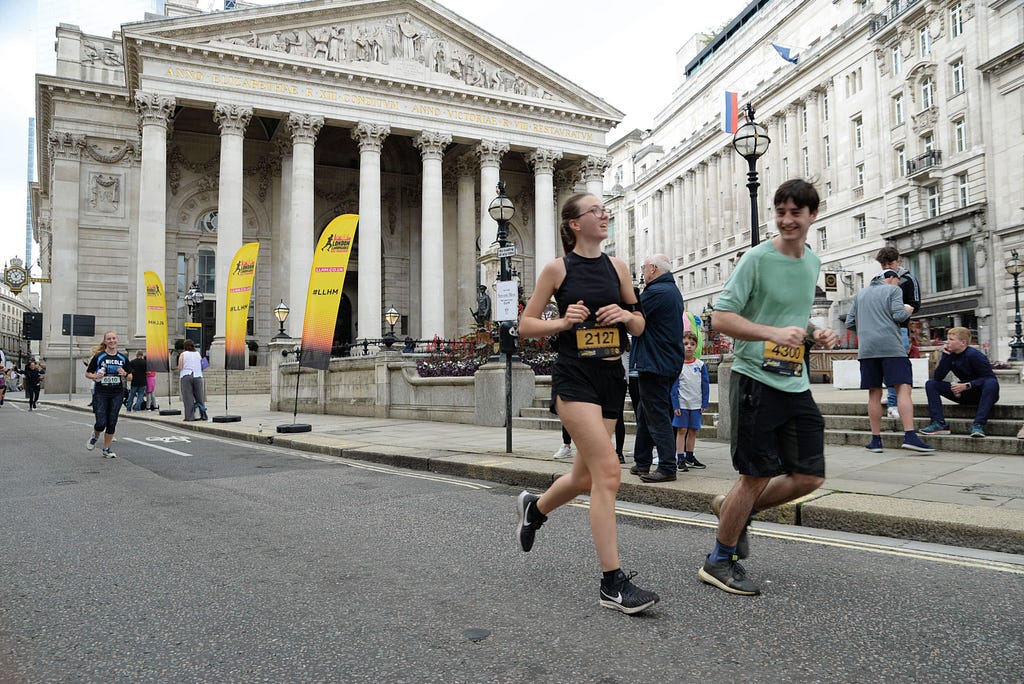 A man and woman run alongside each other through London