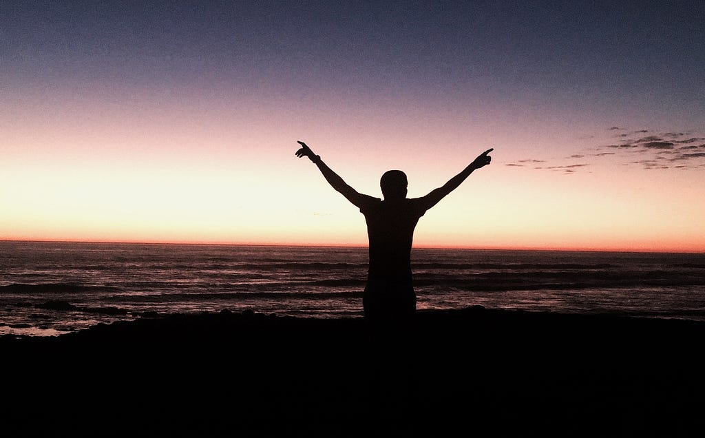 A gay man, experiencing freedom on a beach at sunset