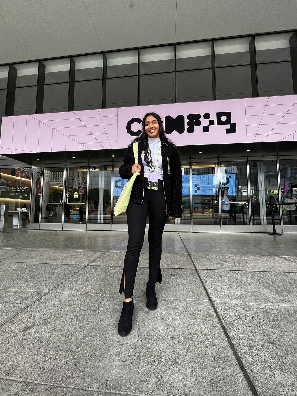 The author Anvitha stands in front of the Config banner at the Moscone center, sporting the fluorescent tote bag and name tag from Figma