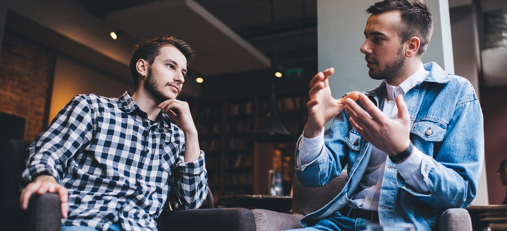 Photo of two men engaging in a discussion. Photo Credit: Adobe Stock Images.