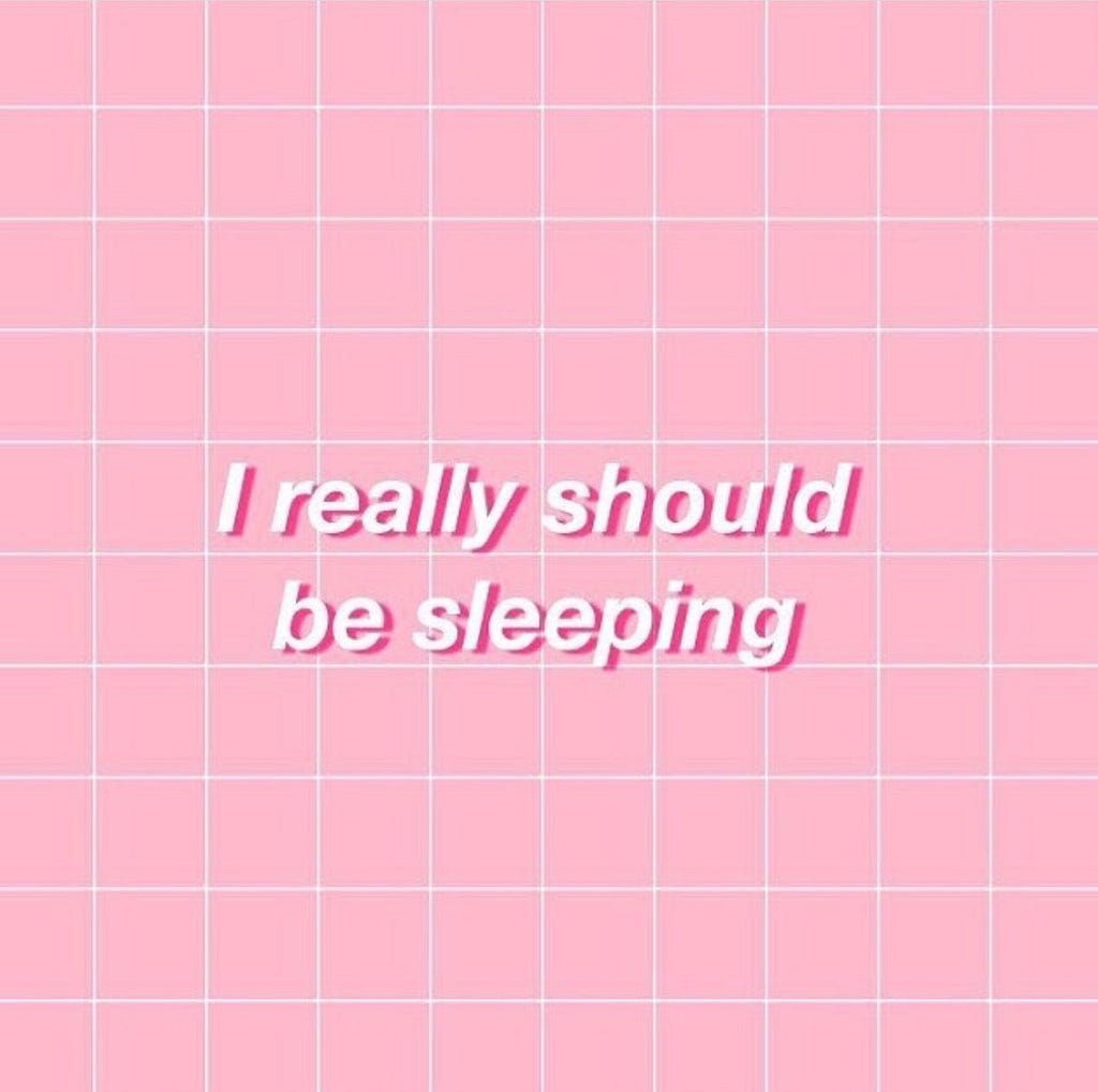 It says: I really should be sleeping in cutesy pink letters and a white grid background.