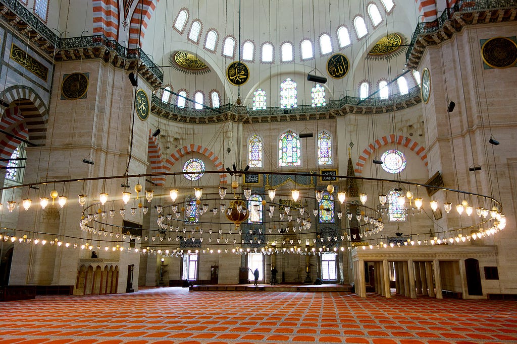 a massive chandelier hanging just above the ground inside a mosque