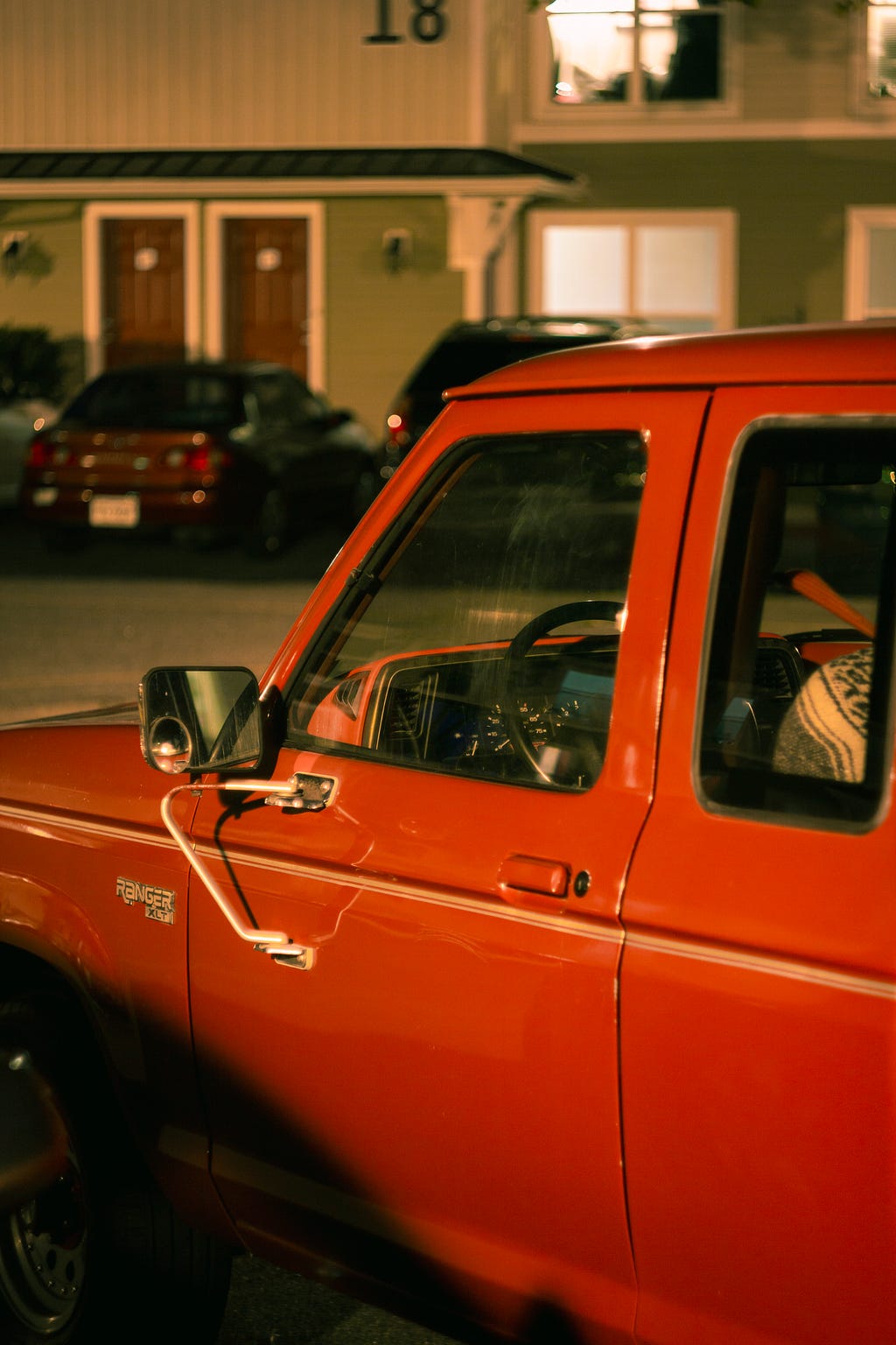 tightly-framed photo of an old red pickup truck late at night