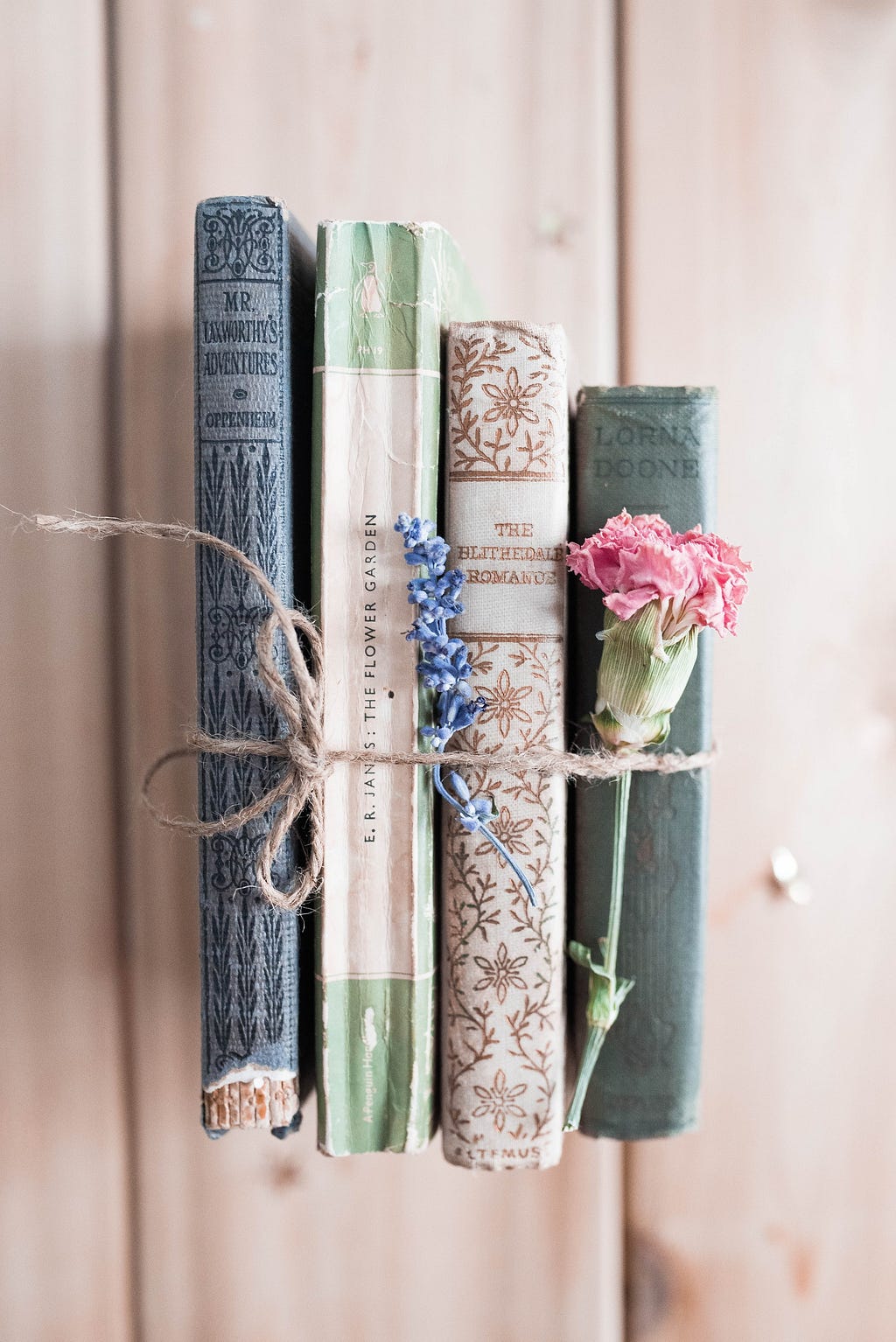 Four assorted vintage books and pink rose tied together with sisal rope