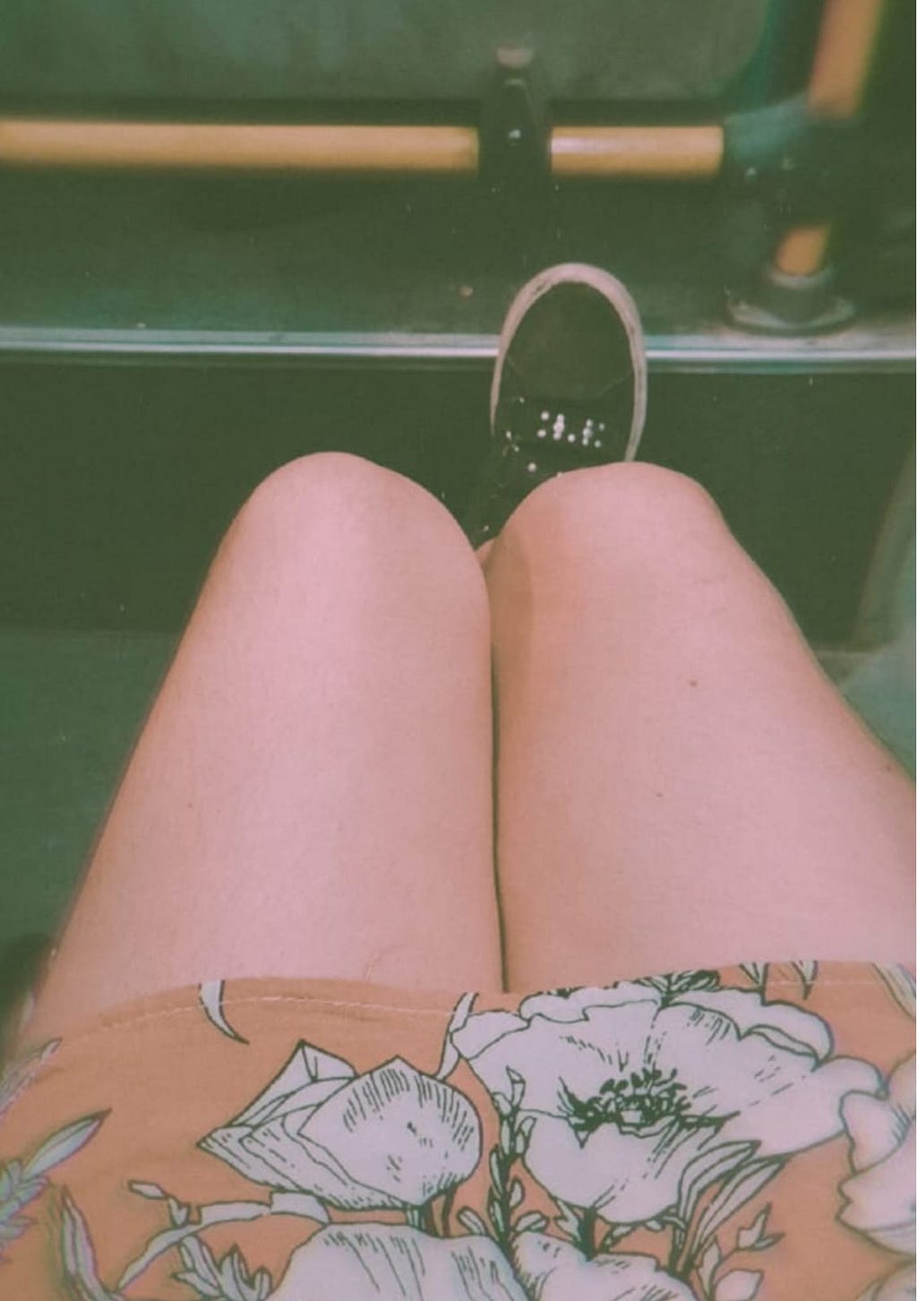 Fotografía de las piernas de Gianna mientras viaja en bus. Se ve una parte de su vestido amarillo con flores blancas.
