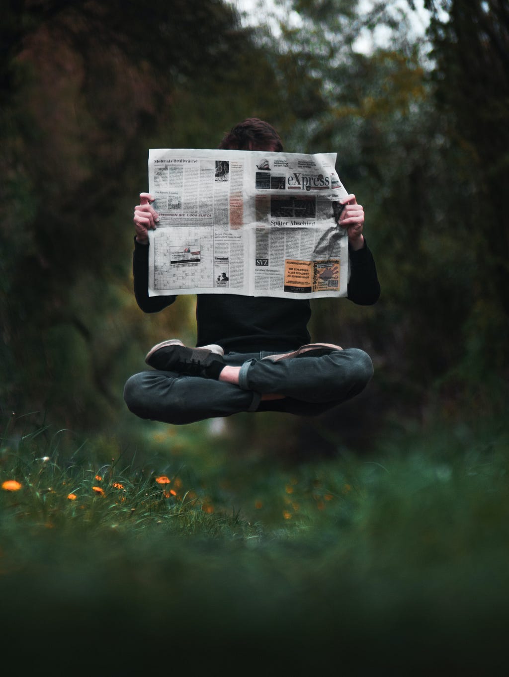 Photo by Julius Drost — https://unsplash.com/@juliusdrost Image of person reading a newspaper in the woods