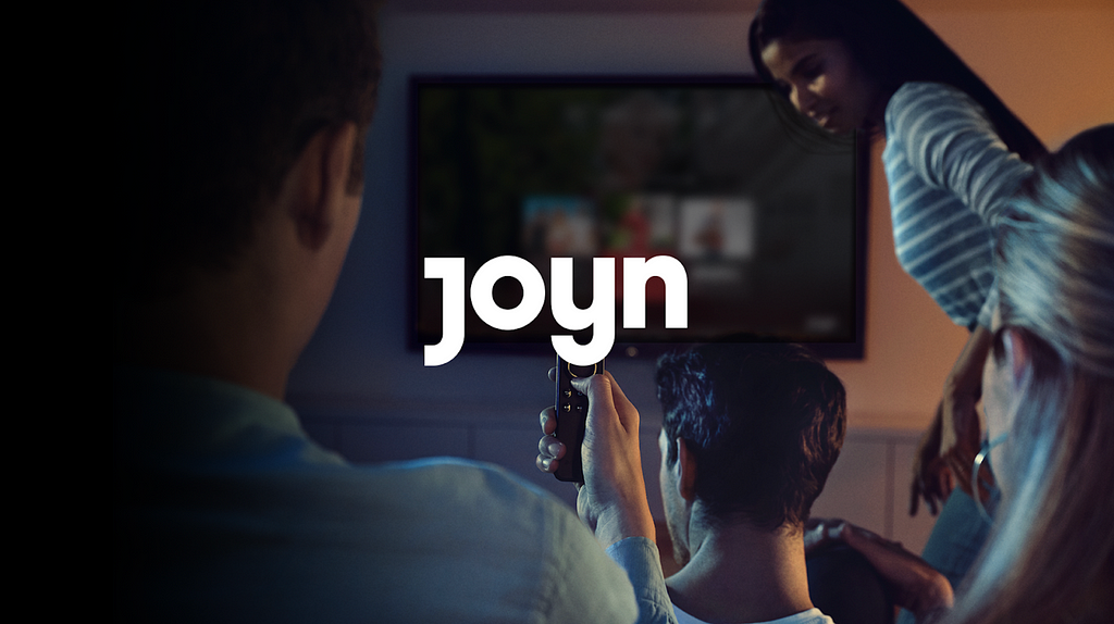 Picture of three people in front of a TV. The word “Joyn” is in the middle of the picture.