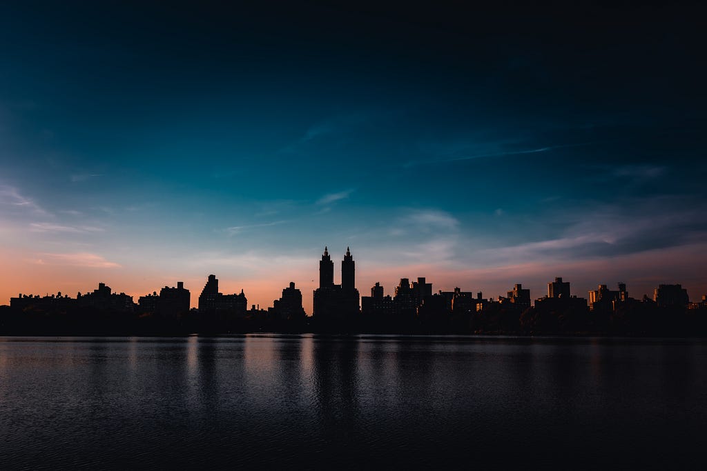 a different New York City skyline as seen from the reservoir in Central Park at sunset