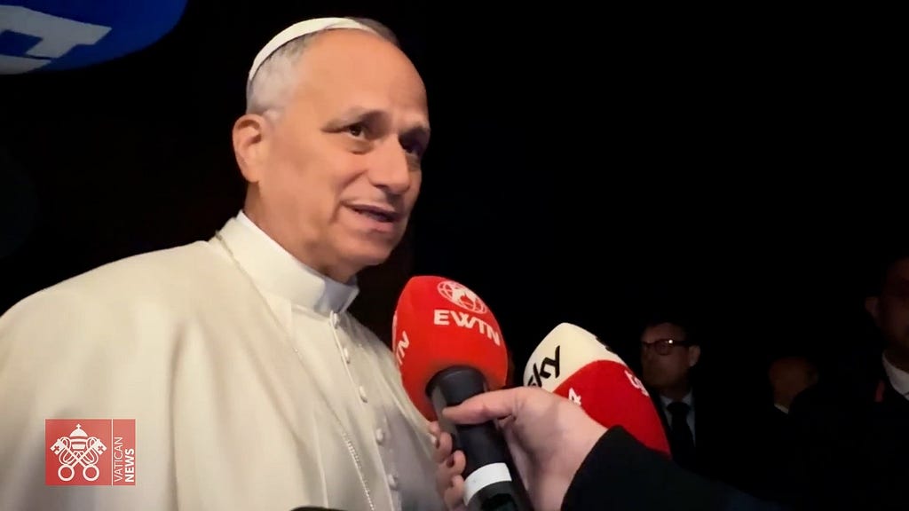 Pope Leo standing in front of media microphones to answer question on the spiritual needs of immigrants being detained in the U.S.
