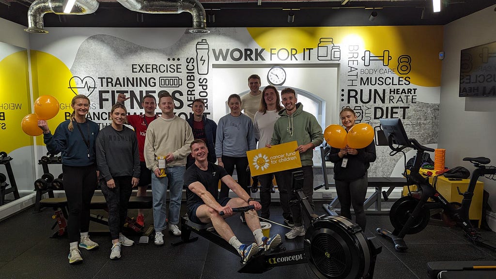 Image of a team of ASOSers posing by a rowing machine in the gym