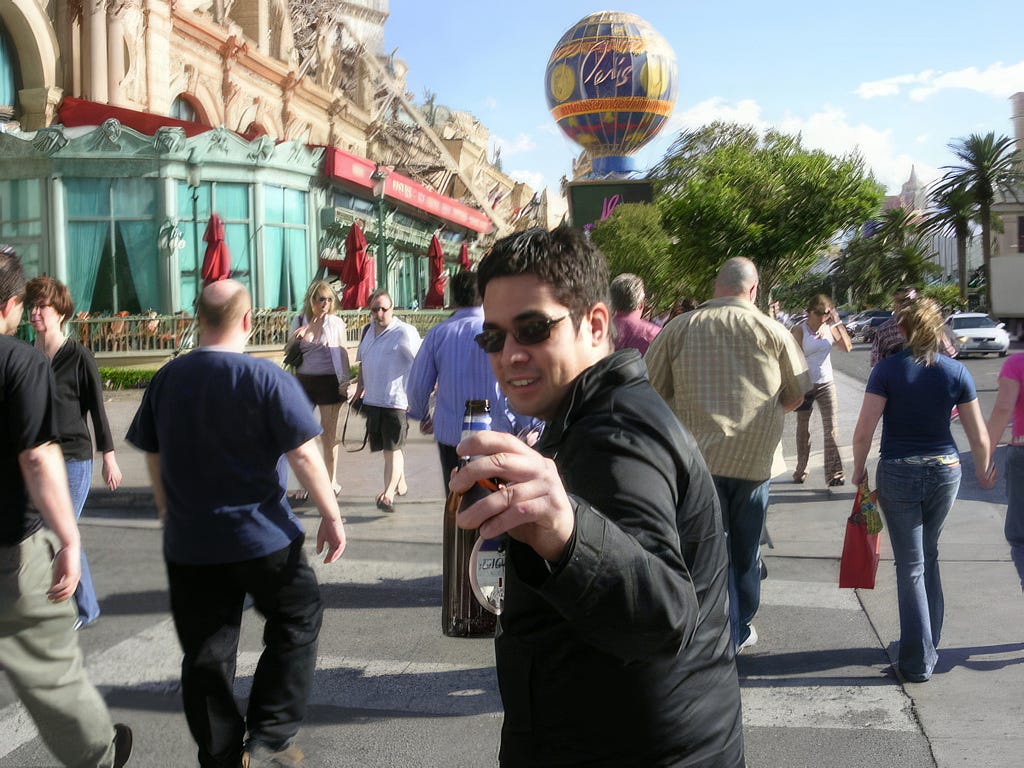 Juan walking down the street, holding beer up to the camera in a farewell fashion