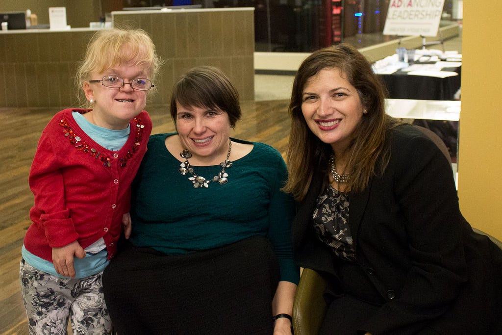 Karen: center, smiling in a green top. To her left: a teenage girl in a cardigan. To her right: a young woman in a blazer.