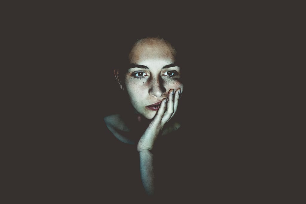 Woman resting head on hand, pensive.