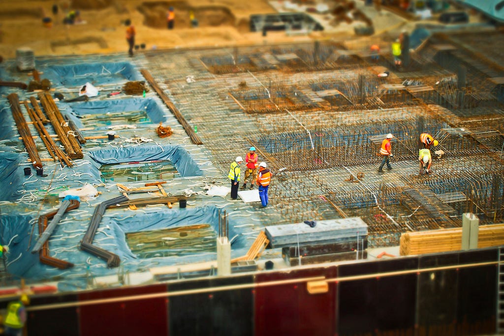 A tilt shift image of a commercial construction site at the foundation stage of completion